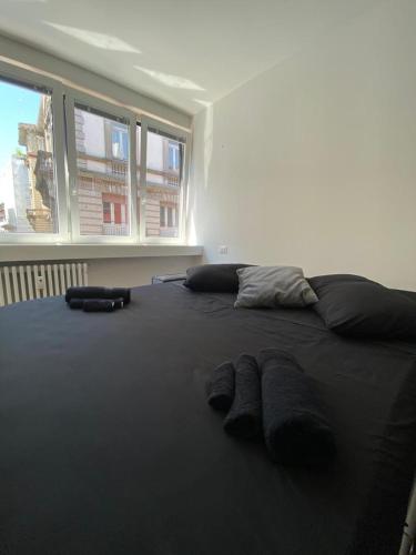 a black bed with two pairs of slippers on it at [Udine Centro] Ade Apartment in Udine