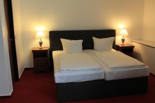 a bedroom with a bed with two lamps on two tables at City Hotel Essen in Essen