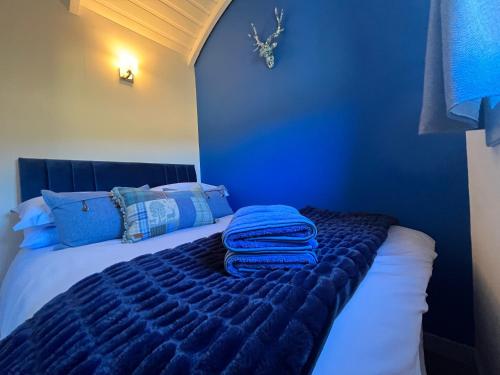 a blue bedroom with a bed with two towels on it at The Stag Hut in Milton