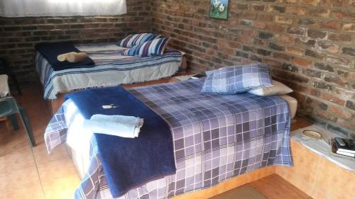 Dos camas en una habitación con una pared de ladrillo. en Onze Rust Guest House and caravanpark, en Colesberg