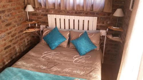 a bed with blue pillows in a room at Onze Rust Guest House and caravanpark in Colesberg