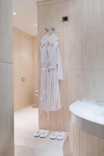 a bathroom with a robe hanging on a wall at Lux Garden Hotel in Azuga