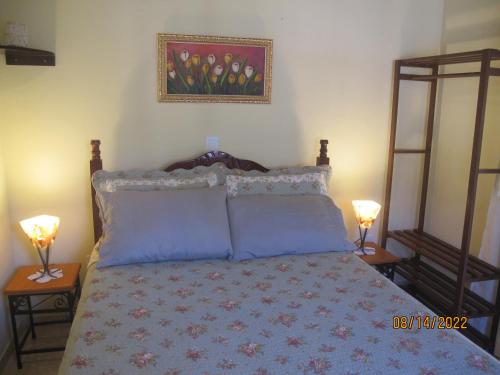 a bedroom with a bed with blue pillows and two lamps at Janela dos Meus Sonhos in Penedo