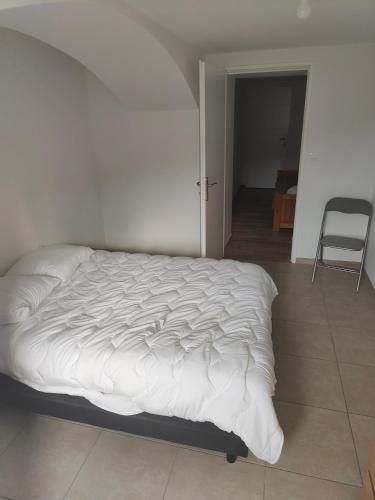 Cama blanca en habitación con silla en Bonjour appartement T2 neuf., en Malleval