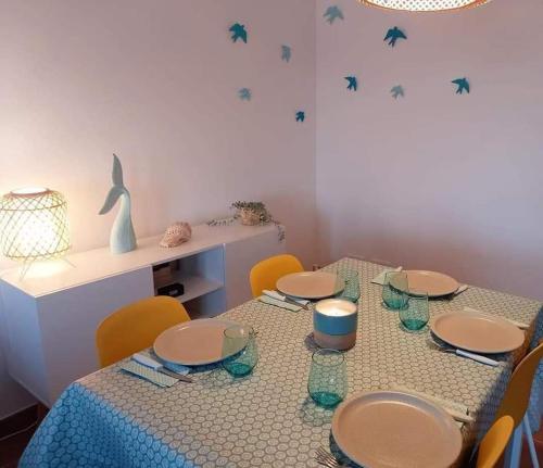 einen Tisch mit Stühlen, Tellern und Gläsern darauf in der Unterkunft Beach House - Casa de Férias MONTE CLÉRIGO in Aljezur