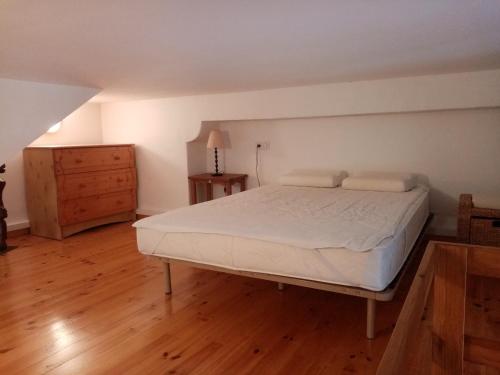 Schlafzimmer mit einem weißen Bett und Holzboden in der Unterkunft Charmant gîte avec parking gratuit sur place. in Davézieux