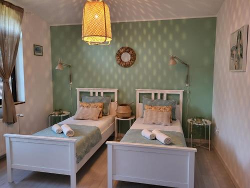 a bedroom with two beds and a chandelier at Sobe Pilajevo 2, 183 Ulica Stjepana Radića, Gola in Gola
