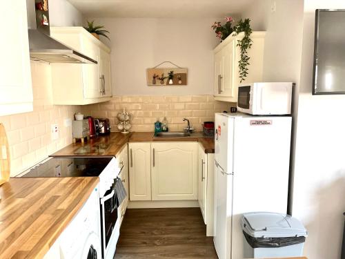 a kitchen with white cabinets and a white refrigerator at Trinity Apartments Four 1-Bedroom Apts Waterford City Centre in Waterford