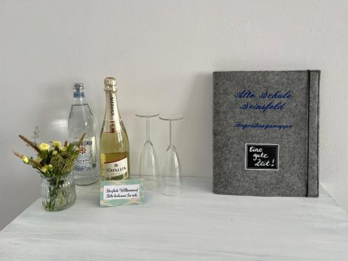 a bottle of wine and two wine glasses on a table at Alte Schule Seinsfeld in Seinsfeld
