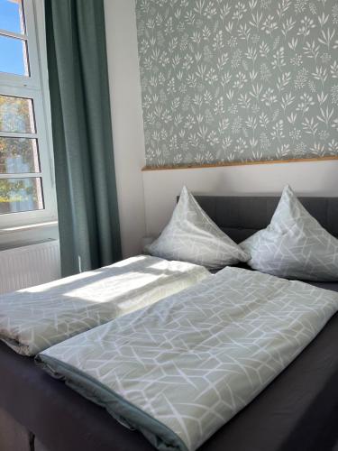 a bed with two pillows and a painting on the wall at Alte Schule Seinsfeld in Seinsfeld