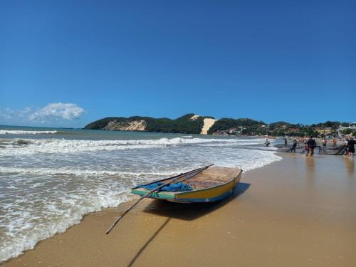 un barco en la playa con gente en el agua en Ilusion Flats Aconchego de Ponta Negra, en Natal