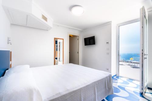a white bedroom with a large bed and a balcony at La Vigna di Bacco in Furore