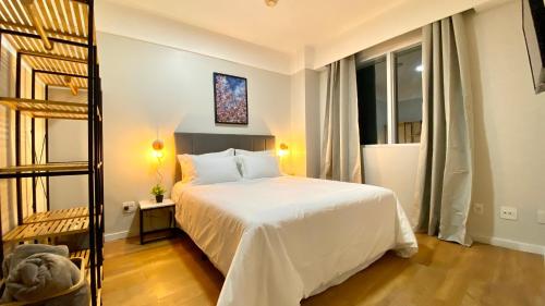 a bedroom with a white bed and a large window at STD - Anora Spaces - Stadium Alphaville in Barueri