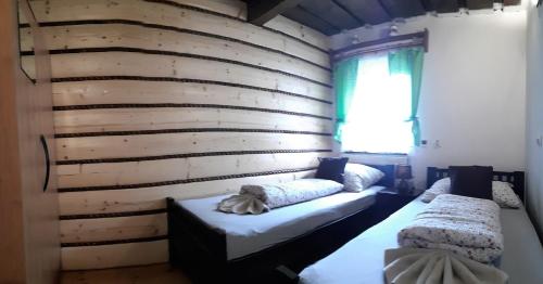 two beds in a room with a wooden wall at Chalupa pri vodopade in Lúčky