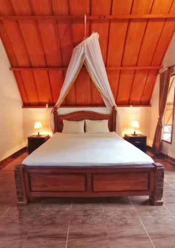 a bed in a room with a wooden ceiling at Follow The Rabbit Bungalow in Gili Air