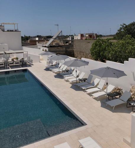 Una piscina con sillas y sombrillas al lado de un edificio. en Azalea Suite Deluxe, en Sannicola
