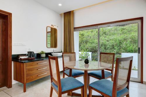 een eetkamer met een tafel en stoelen en een raam bij Pakoid Cottages in Idukki