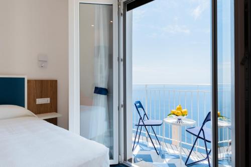 a bedroom with a bed and a balcony with a table and chairs at La Vigna di Bacco in Furore