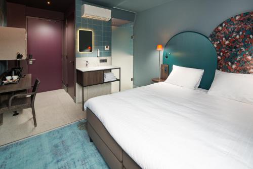 1 dormitorio con 1 cama grande y baño en Hotel Babylon Heerhugowaard - Alkmaar, en Heerhugowaard