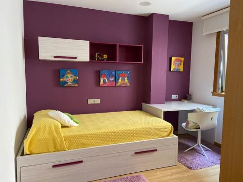 1 dormitorio con cama amarilla y pared morada en Apartamento con vistas al mar, en Malpica de Bergantiños