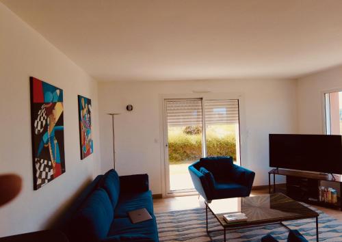 een woonkamer met een blauwe bank en 2 stoelen bij maison récente totalement rénovée vue mer panoramique in Penvénan