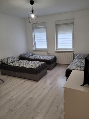3 camas en una habitación con suelo y ventanas de madera en Kobierska 8 Mieszkanie 2, en Krotoszyn