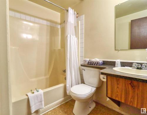 a bathroom with a toilet and a sink and a shower at Kings Court Motel in Cold Lake