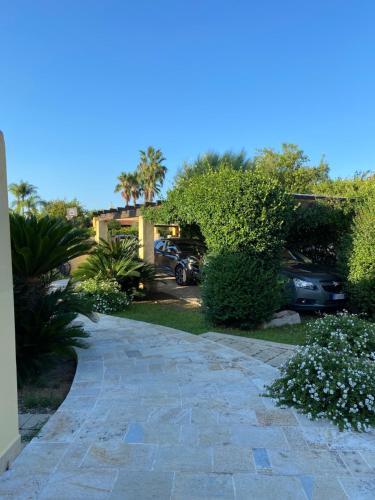 una pasarela de piedra en un patio con coches aparcados en Maxi Villa Antiope Argonauti Resort en Marina di Pisticci