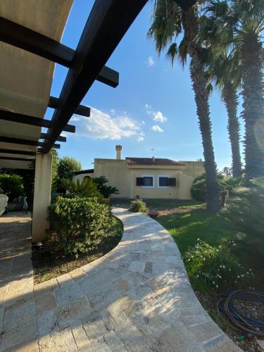 una casa con palmeras y una pasarela en Maxi Villa Antiope Argonauti Resort en Marina di Pisticci