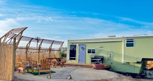 einem grünen Wohnwagen mit einem Tisch und einer Terrasse in der Unterkunft Rustic Farm meadow stay in Temecula