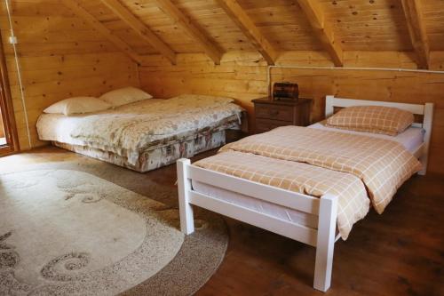 a bedroom with two beds in a wooden cabin at Apartmani Kajkut in Banja Luka