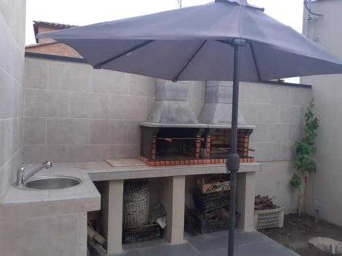an umbrella in front of an outdoor oven at Villa Piscine in Montady