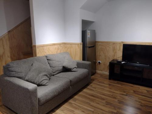 a living room with a couch and a flat screen tv at Departamentos Kitkaika in Punta Arenas