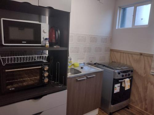 a small kitchen with a stove and a microwave at Departamentos Kitkaika in Punta Arenas