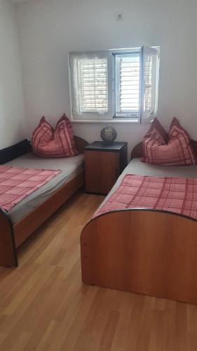 twee bedden in een kamer met houten vloeren en ramen bij Apartment Julian in Kamenari