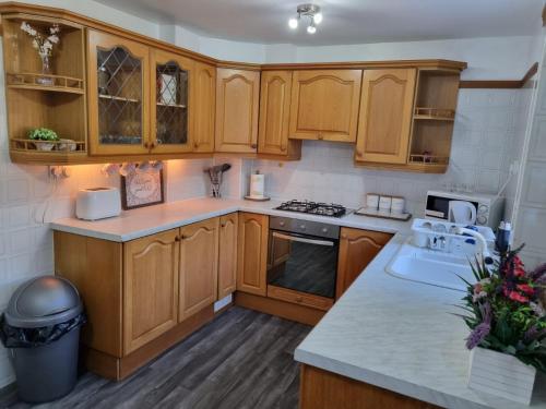 a kitchen with wooden cabinets and a sink at Centrally Located w/ Free Parking & Smart TV in Leeds
