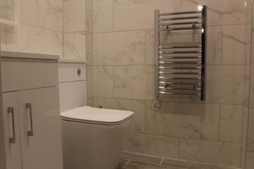 a white bathroom with a toilet and a shower at High-End Central Luton Studio - Ideal for Airport! in Luton