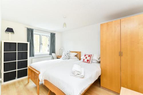 a bedroom with two beds and a wooden cabinet at Modern 4 bedroom Terraced House by the Thames in London
