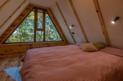 a bedroom with a bed and a large window at Log cabins Banjska stena in Mitrovac