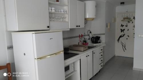a kitchen with white cabinets and a white refrigerator at Studio Almudena in Torrevieja