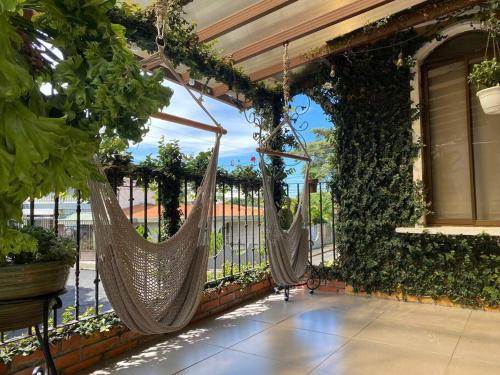 a porch with two hammocks hanging from a building at Airport SJO Residence - Edward & Familia Inn in Alajuela