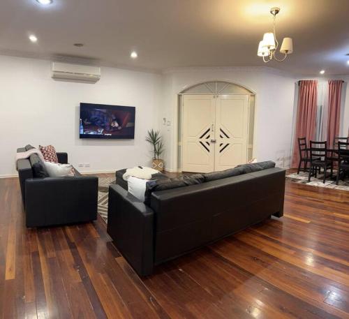 two black couches in a living room with wood floors at Affordable getaways in Caroline Springs