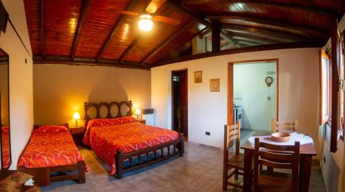 1 dormitorio con 1 cama, mesa y sillas en La Casona Cabañas en Villa Ciudad Parque