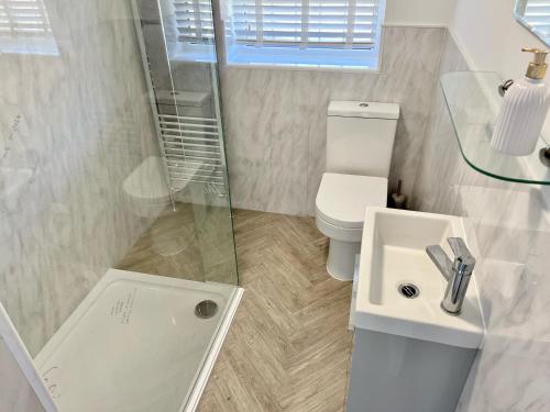 a white bathroom with a toilet and a sink at The Terrace - Tankerton in Kent