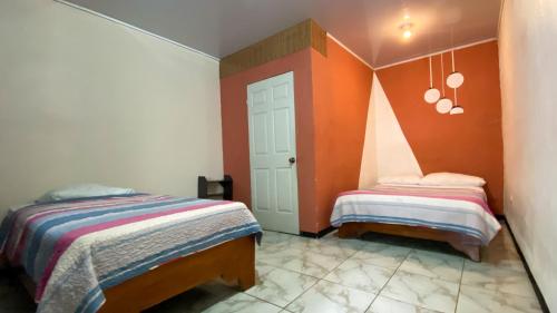 two beds in a room with orange walls at Mi Casa Tica Backpackers in Monteverde Costa Rica