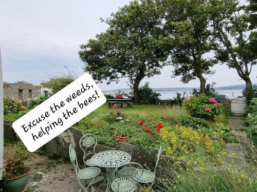 a sign in a garden with chairs and flowers at Bay View House in Liscannor