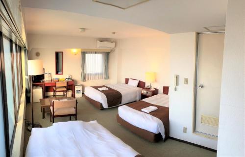 東京にあるスカイハートホテル小岩のベッド2台とデスクが備わるホテルルームです。