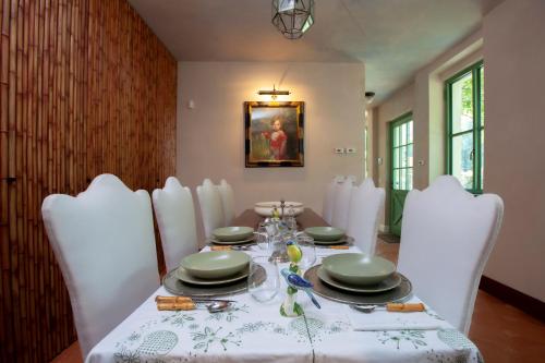 a dining room with a table and white chairs at The Greenhouse Luxury Villa on Lake Como in Como
