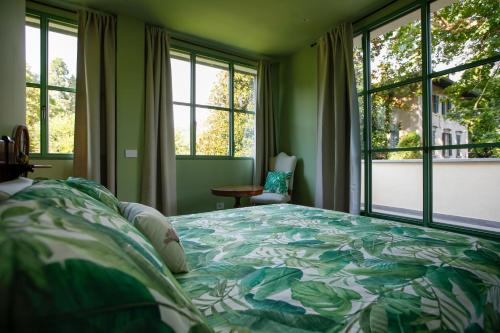 a bedroom with a bed with a green bedspread and windows at The Greenhouse Luxury Villa on Lake Como in Como
