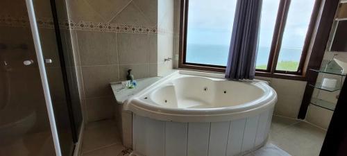 a large white tub in a bathroom with a window at Sentinelas do Mar in Arraial do Cabo